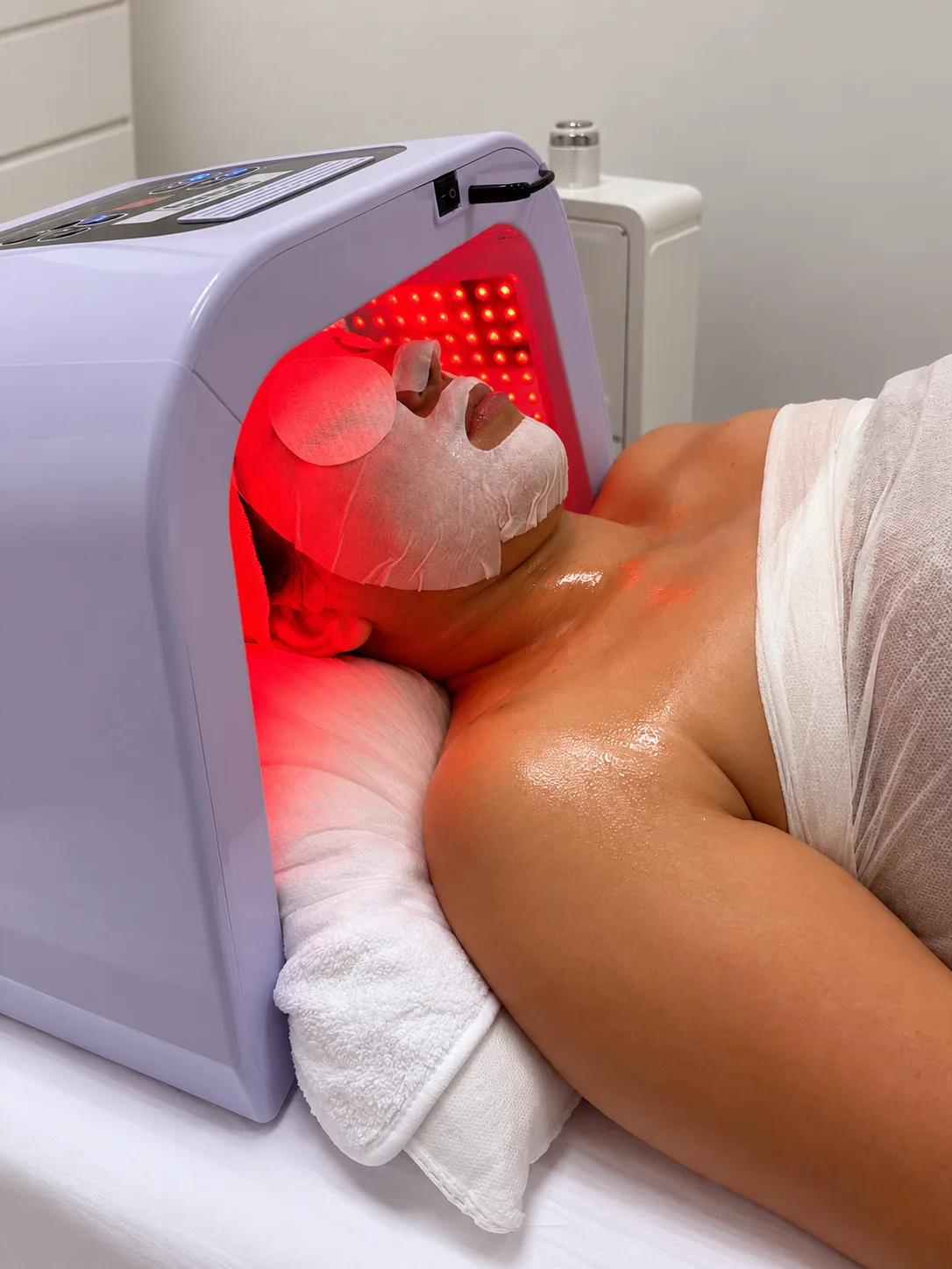 Lichttherapie bei KOYO: Kundin unter der LED-Haube mit Tuchmaske